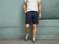 Man in een wit T-shirt en blauwe shorts