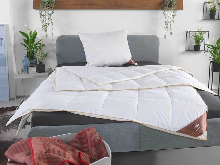 Een wit dekbed van Halssen met een beige rand op een grijs bed.