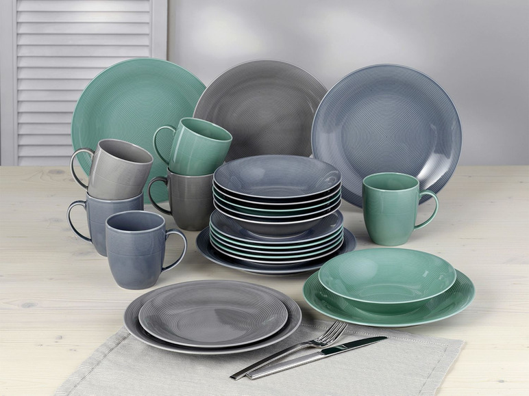 Een set serviesgoed met groene en grijze borden en bekers.