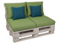 Witte houten palletbank met groene kussens en blauwe sierkussens.