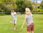 Twee mensen spelen badminton op een grasveld.