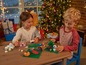 Twee kinderen bouwen kerstthema LEGO sets aan een tafel.