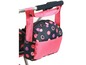 Een roze en zwarte tas met stippen, bevestigd aan een kinderwagen.