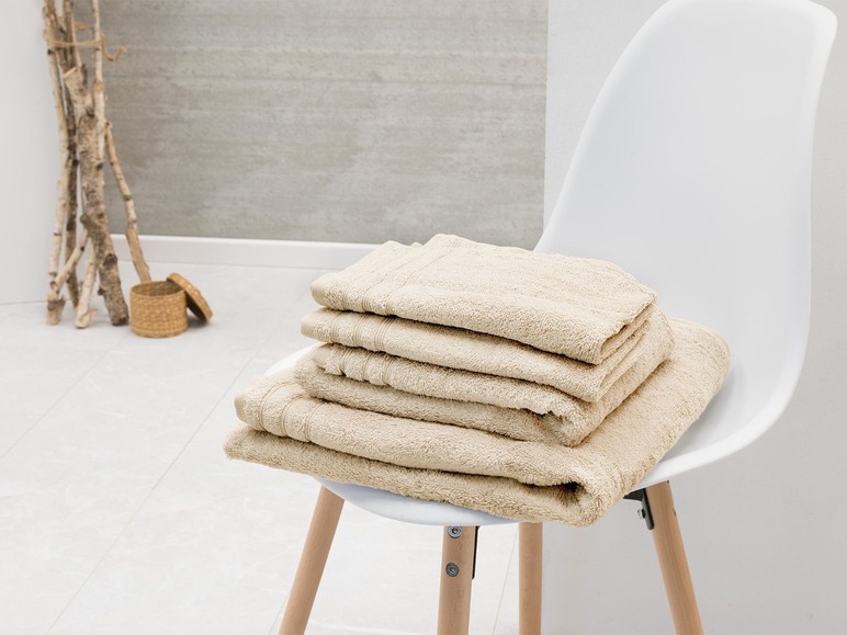 Beige badhanddoeken op een witte stoel.