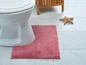 Een witte toiletpot met een roze badmat op een betegelde vloer.