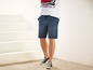 Een man draagt blauwe denim shorts en witte sneakers.
