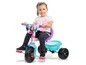 Een kind op een roze en blauwe driewieler met Frozen-thema.