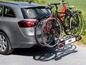 Twee fietsen op een fietsendrager achter een grijze auto.