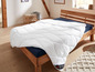 Een wit dekbed met 3M Thinsulate op een houten bedframe.
