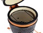 Een zwarte kamado-grill met een oranje rand, open met een rooster.