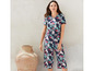 Een vrouw draagt een blauwe jumpsuit met tropische print.