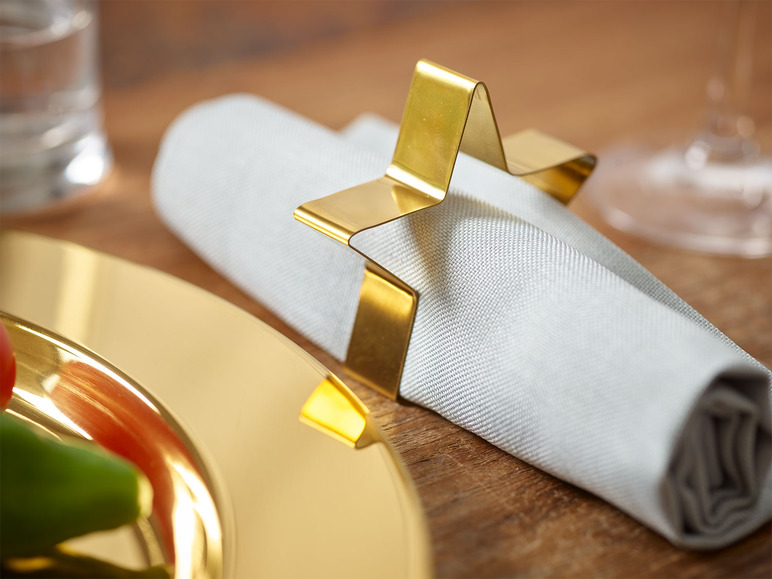 Een gouden stervormige servetring op een witte servet.