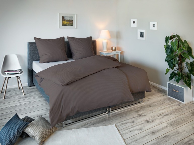 Donkerbruin beddengoed met gestreepte satijnen stof in een slaapkamer.