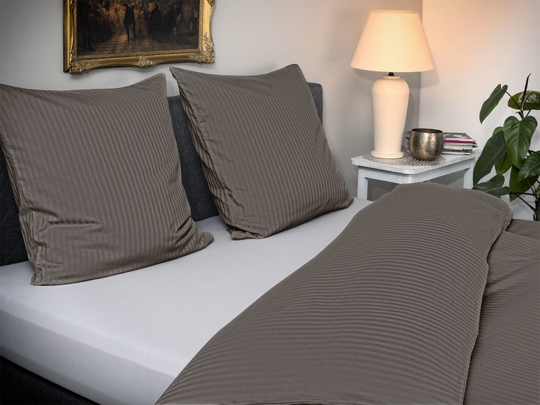 Donkergrijze gestreepte dekbedovertrek en kussenslopen op een wit bed.