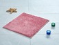 Een roze badmat met twee kaarsen