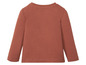 Een terracottakleurig longsleeve shirt voor baby's.
