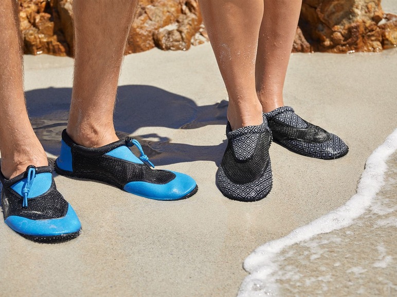 Twee paar blauwe en zwarte waterschoenen op het strand.