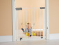 Een baby achter een witte veiligheidspoort van Summer Infant.