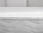 Een wit matras topper op een matras met een rits.