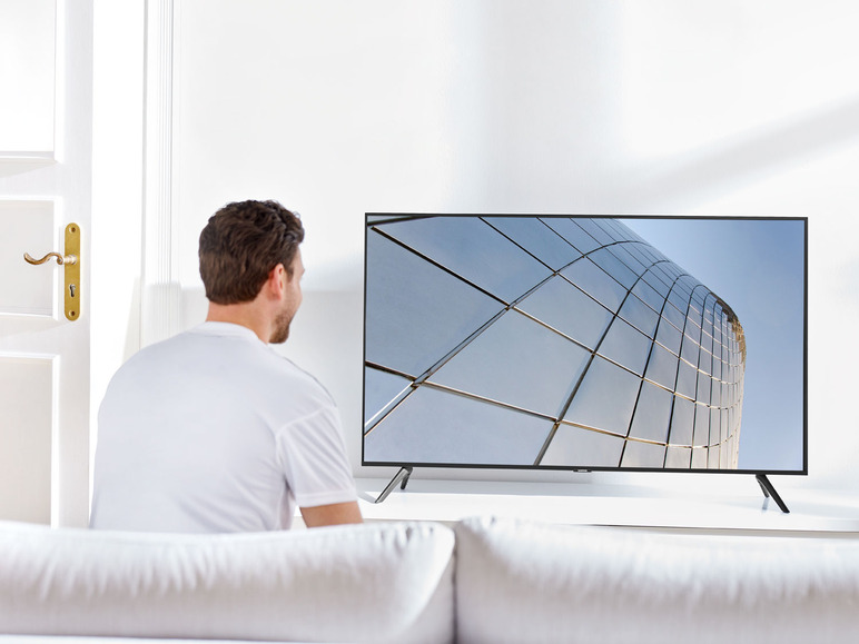 Man kijkt tv met een modern gebouw op het scherm.