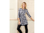 Een vrouw draagt een geruit overhemdjurk met een ceintuur.