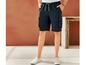 Man draagt blauwe cargo shorts met witte sneakers.