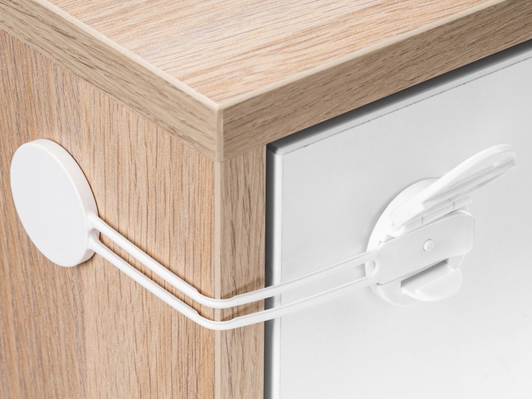 Witte kinderbeveiligingssloten op een houten kastlade.