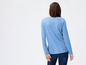 Vrouw draagt een blauwe longsleeve en jeans.