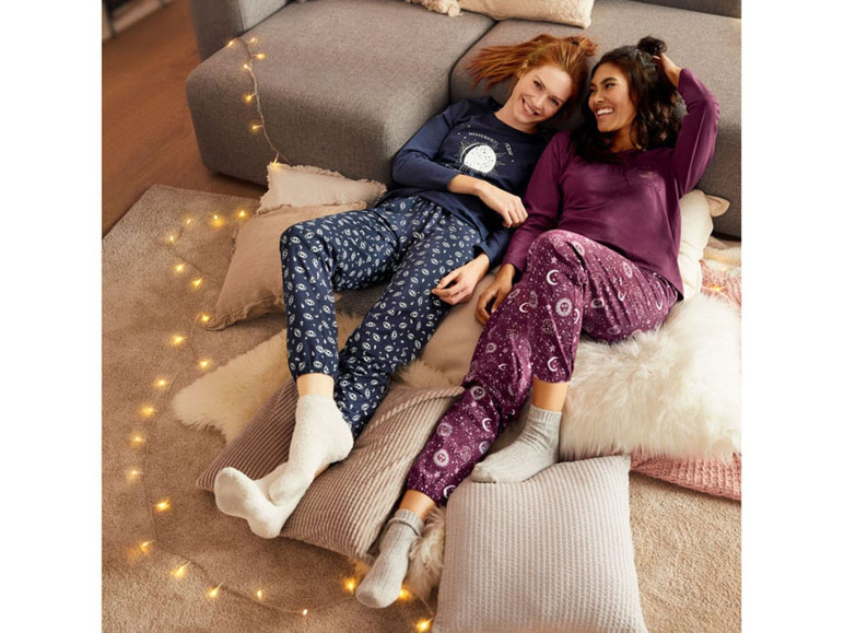 Twee vrouwen dragen pyjama's met een maan- en sterrenprint.