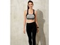 Een vrouw draagt een zwarte sportbeha en leggings.