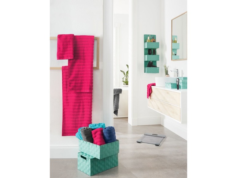 Badhanddoeken, opbergmanden en een badkamerschaal in een moderne badkamer.