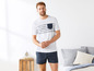 Man in wit T-shirt met blauwe strepen en blauwe shorts.