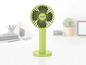 Een groene draagbare ventilator van Uno, op een witte tafel.