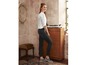 Een vrouw draagt een wit blouse met stippen en zwarte skinny jeans.