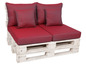 Een witte houten palletbank met rode kussens.