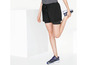 Een vrouw draagt zwarte sport shorts en blauwe sneakers.