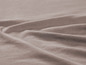 Een close-up van een gladde, gekreukelde stof in een beige tint.