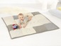 Een baby op een patchwork speelkleed met een bal.