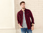 Man draagt een rood-zwart geruit overhemd, een grijs T-shirt en blauwe jeans.