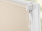 Beige rolgordijn met wit koord en bevestigingssysteem.
