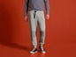 Man draagt grijze joggingbroek met zwarte details en blauwe sneakers.