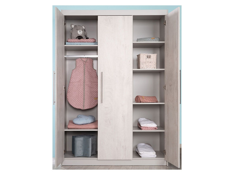 Een kledingkast met baby slaapzak, dekens en speelgoed.