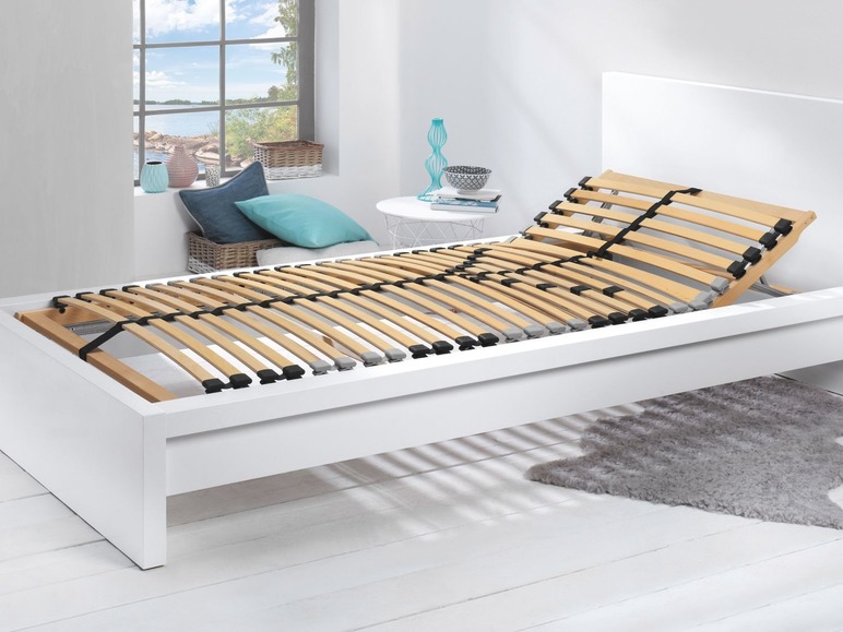Een wit bedframe met een houten lattenbodem.