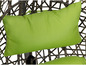 Een groene kussen op een wicker stoel.