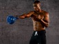 Een man met een blauwe kettlebell tijdens een workout.