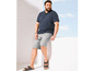 Man draagt een blauwe polo, grijze shorts en sandalen.