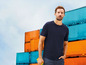 Man in een donkerblauw T-shirt voor een containerterminal.
