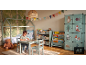 Kinderkamer met huisvormig bed, tafel en stoelen, boekenplanken en bos-thema kledingkast.