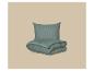 Mintgroen kussen en dekbed met gestreepte textuur op een beige achtergrond.