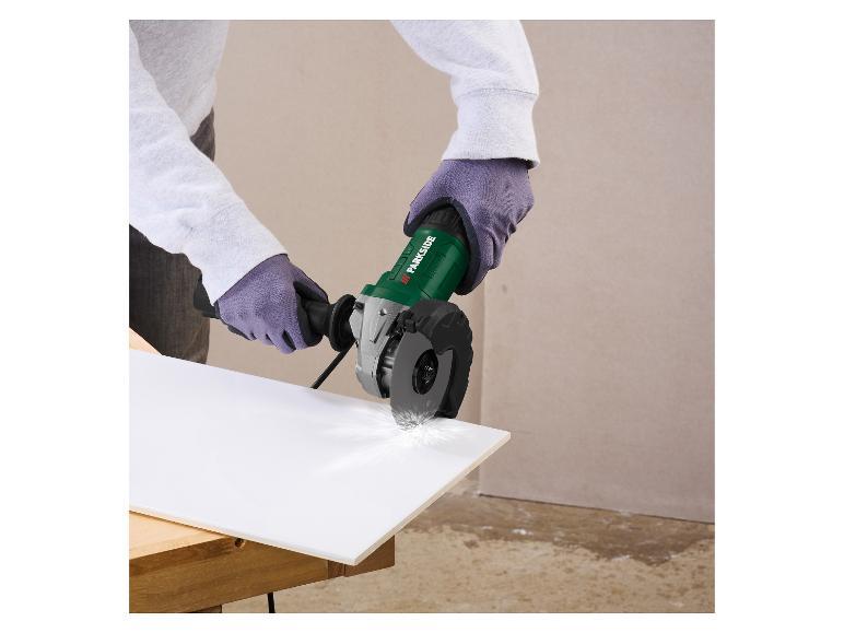 Persoon in handschoenen snijdt een witte plaat met een groene haakse slijper, vonken creërend.